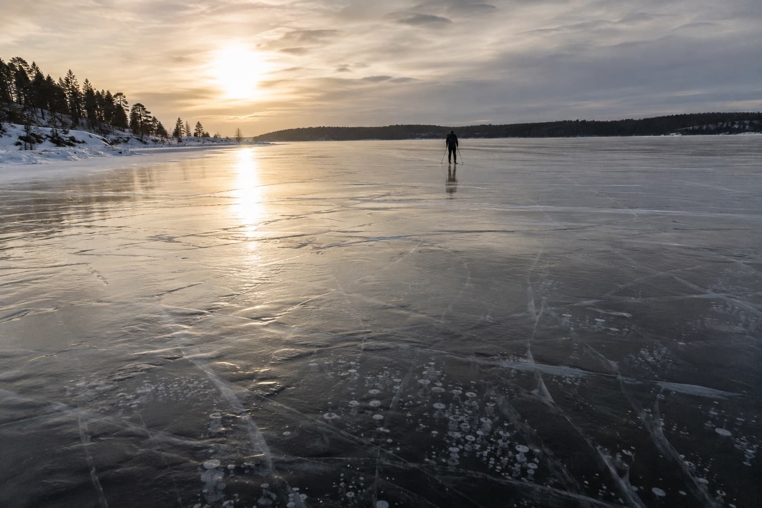 Långfärdsskridskoåkare i silhuett på blank naturis i motljus